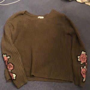 green sweater with flowers on the sleeves